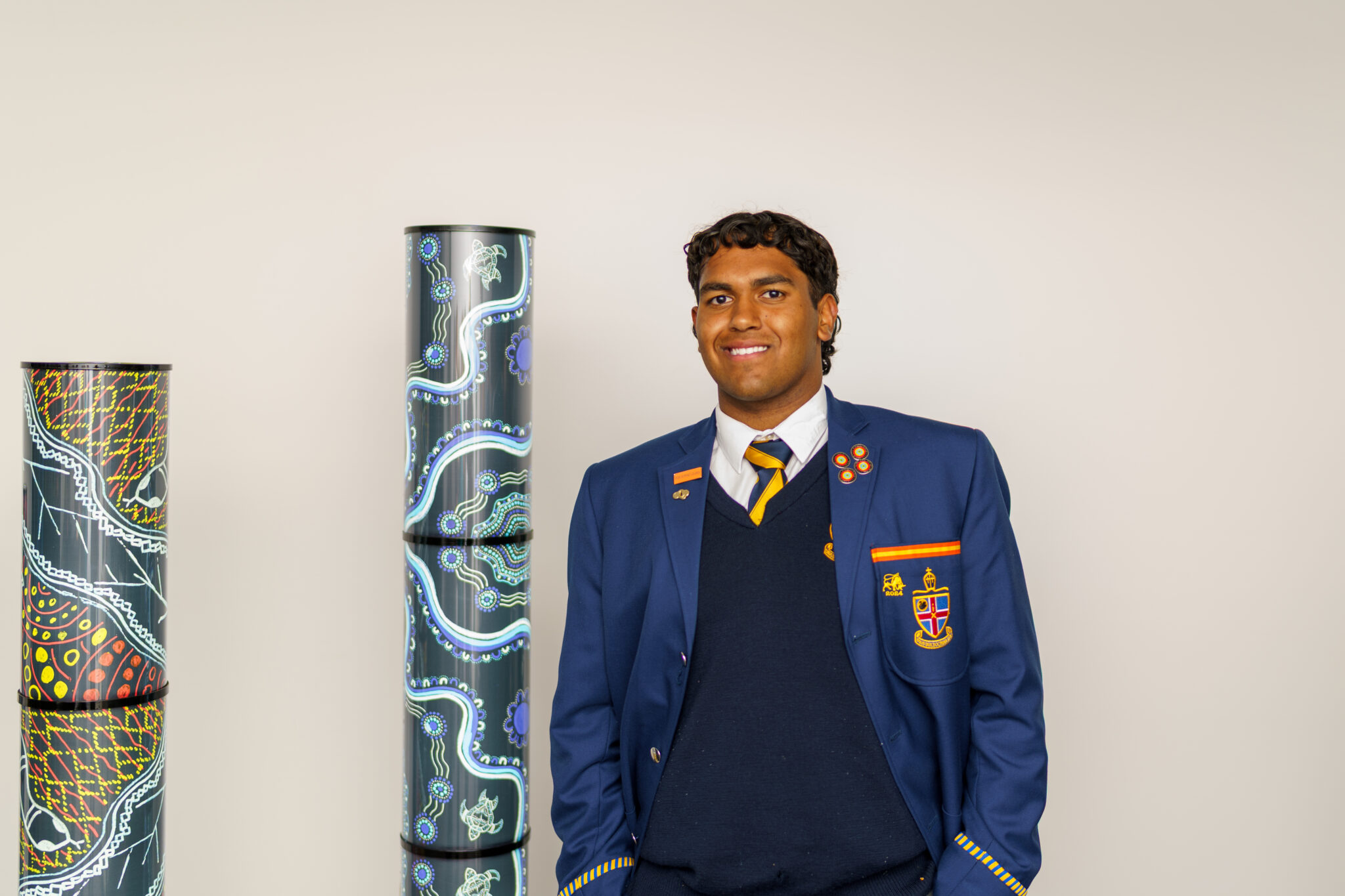 A Aboriginal and Torres Strait Islander Program student standing beside his artwork during the 2025 NAIDOC Week art exhibition