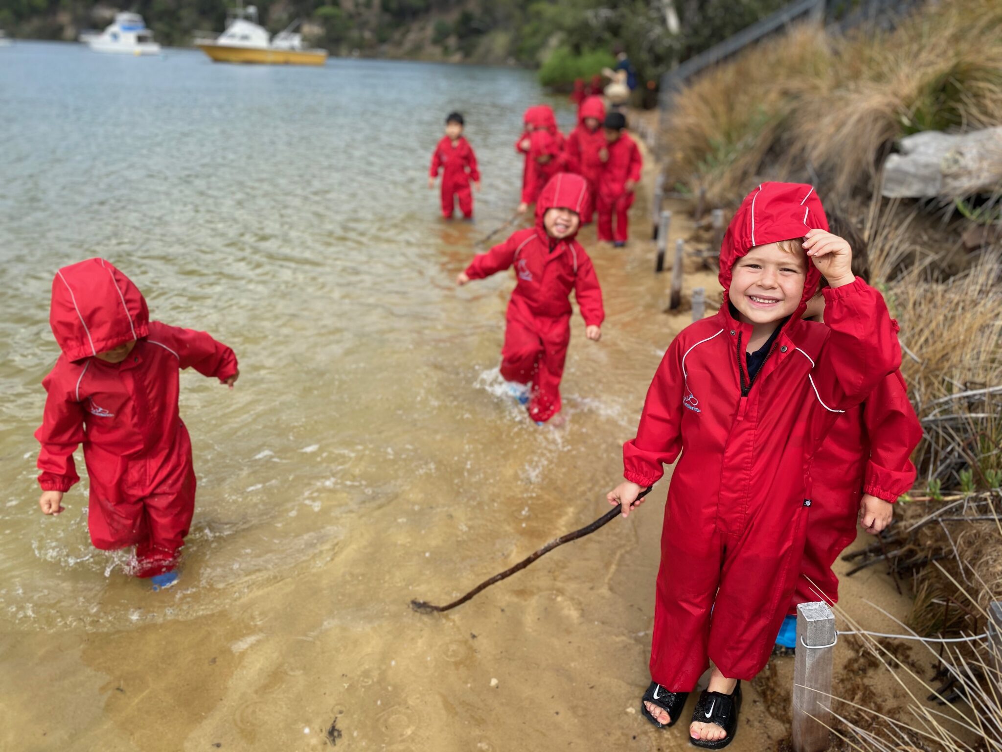 Students in red waterproof jump suits playing in the Swan River