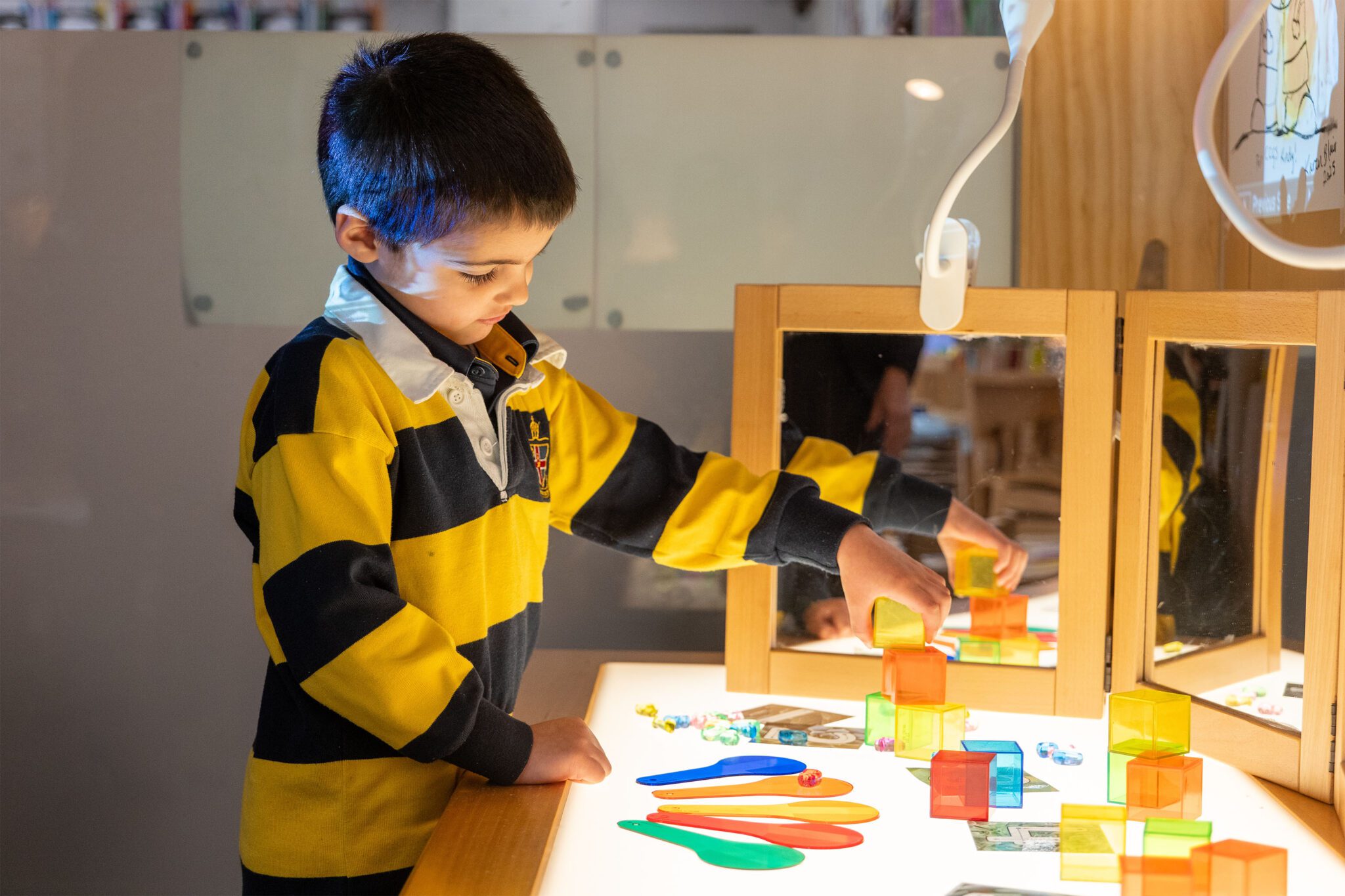 An ELC student playing with coloured blocks at a light table.
