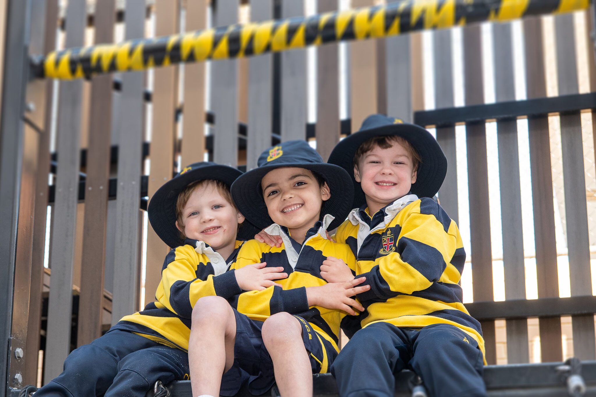 Three ELC students sitting in the playground cubby house