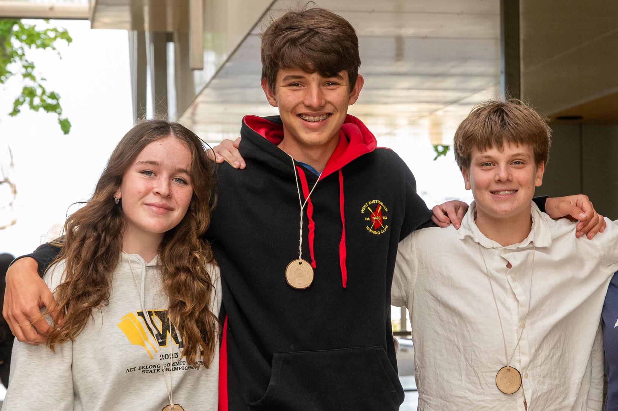 Three students in the On Queenslea Drive (OQD) program join arms, smiling